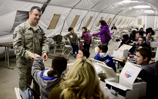 Photo by Staff Sgt. Armando Schwier-MoralesTech. Sgt. Gencian Blushi, 435th Construction and Training Squadron forces support NCO in charge, shows children a Meal, Ready to Eat during their “deployment” April 1 on Ramstein. Ramstein hosted a mock deployment for children at Ramstein Intermediate School.