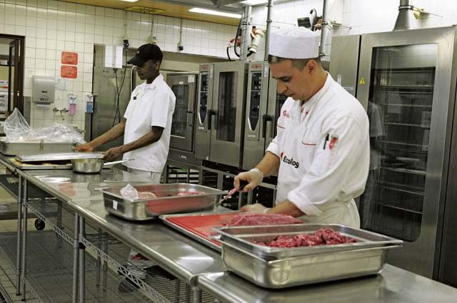 Private 1st Class Kadavius Williams, 21st Theater Sustainment Command food service specialist (left), and a civilian culinary specialist prepare meat for the main-line portion of dinner May 9 at the Clock Tower Cafe on Kleber Kaserne. The Clock Tower Cafe is the 2016 Phillip A. Connelly Department of the Army level Best Garrison Dining Facility.