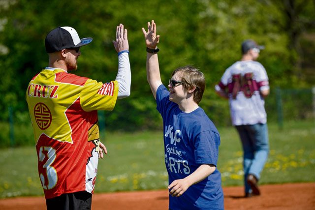 Nick Waller, Guzzler’s softball player and volunteer, high-fives James Lucas, Ramstein Middle School student, during an Adaptive Sports softball game May 2 on Ramstein. The Adaptive Sports games held throughout the year give special-needs students a chance to come together to learn both social and physical skills.