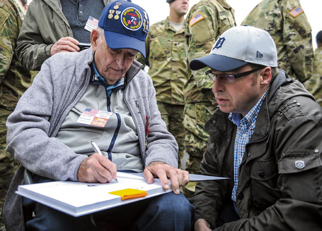 Cliff Goodall, a World War II veteran, signs an autograph after a memorial ceremony June 4 in Angoville-au-Plain, France. The memorial ceremony was in honor of Kenneth Moore and Robert Wright, medics with the 101st Airborne Division during World War II, who provided medical care to Allies and enemies alike at the Angoville-au-Plain church in June 1944.