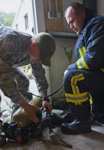 Maj. Tomas Zukauskas, Lithuanian air force firefighter (right), takes his gear off with the help of U.S. Air Force Staff Sgt. Anthony Montano, 435th Construction and Training Squadron contingency firefighting operations instructor, after participating in a training exercise July 11 at Ramstein. The training included close-quarters maneuvers that involved multi-level platforming and retrieving training dummies, as they simulate saving people out of a trapped situation.