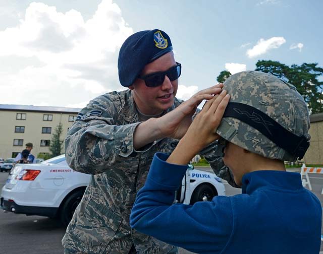 Airman 1st Class Joseph Marsden, 86th Security Forces Squadron security forces member, helps a child put on a helmet during a block party Aug. 5 on Ramstein. The Ramstein Enlisted Club hosted the block party, which included static displays from the 86 SFS and the 86th Civil Engineer Squadron firefighters.