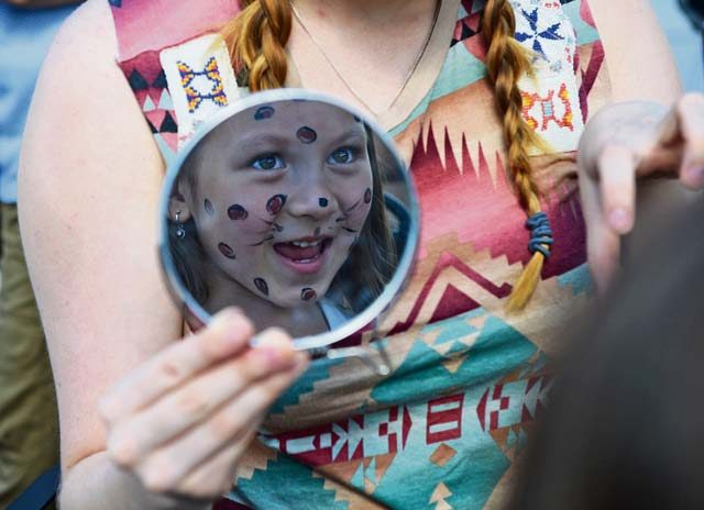 Alycia Lidwell, Ramstein Enlisted Club vault cashier, holds up a mirror for a child after painting her face during a block party hosted by the Ramstein Enlisted Club Aug. 5 on Ramstein.