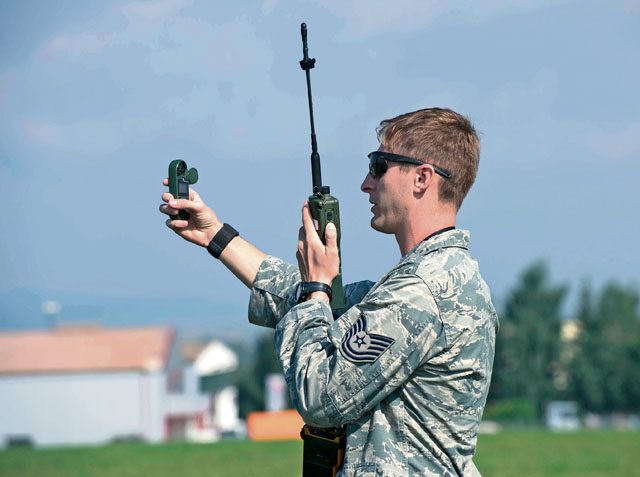 Tech Sgt. Luke Hightower, 435th Contingency Response Group contingency air traffic controller, uses a wind meter and radio to communicate drop zone calculations July 27 at Bitburg Airfield, Germany. Contingency ATCs analyze variables such as altitude, surface winds, load type, aircraft speed and DZ size in order to assist aircraft personnel in safely dropping cargo or personnel.