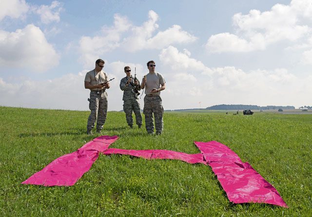 Contingency air traffic controllers from the 435th Contingency Response Group stand behind an aircraft visual reference July 27 at a drop zone at Bitburg Airfield, Germany. Contingency ATCs assisted with International Jump Week by communicating with aircraft and airfield personnel to coordinate safe drops of cargo and personnel.