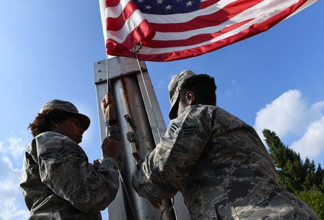 Airman 1st Class Bria Jackson, 786th Civil Engineer Squadron emergency management specialist (left), and Senior Airman Daneeka Mucker, 86th Logistics Readiness Squadron HAZMART pharmacy specialist, lower the American flag during a 9/11 memorial retreat ceremony Sept. 9 on Ramstein. 