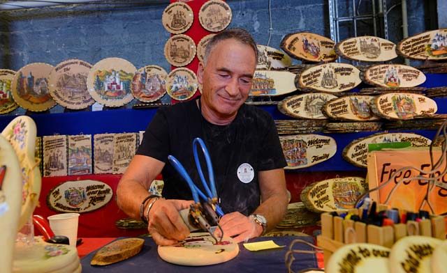 Photo by Senior Airman Timothy Moore Martin Reimlinger engraves a piece of wood Sept. 19, 2015, on Ramstein. Reimlinger was one of many vendors present at the 51st Ramstein Bazaar to showcase his merchandise.