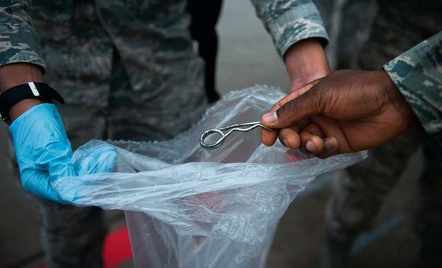 An Airman drops a piece of metal into a trash bag during a foreign object damage prevention walk Sept. 20 on Ramstein. The Ramstein Bazaar was held earlier this month, and over 300 Airmen came to participate in a FOD walk after the event to pick up any remaining debris left behind.