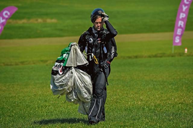 Photo by Senior Airman Nicole Keim A skydiver walks with his parachute after landing a jump Aug. 13 in Wallerfangen, Germany. The jumper had an average of five skydiving jumps per day. 