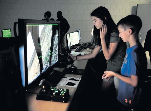 Family members test out a flying simulation during an open house Aug. 25 on Einsiedlerhof Air Station. The simulators are modeled after different areas of deployed locations and allow Airmen to train and hone their skills for real-world situations.