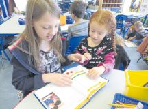Amilin Onigkeit, fifth-grader in Maxine Reid’s class (left), and KeighLynn Causey, first-grader in Gabriele Arseneault’s class, read together about math games during a multiage partial German immersion class Sept. 21 at Landstuhl Elementary Middle School.