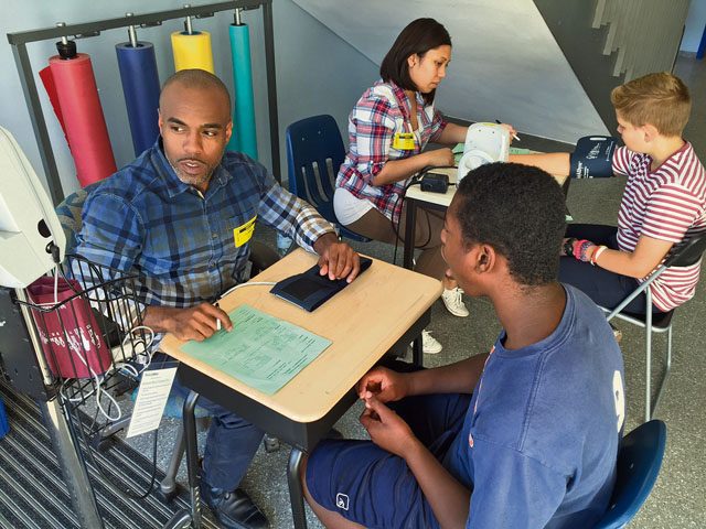 Tech. Sgt. Lavar Plummer, 86th Civil Engineer Group (front left), prepares to record student Joseph Martin’s blood pressure results while Ammon Waite (back right) has his blood pressure checked by Staff Sgt. Jessica Loza, 435th CRG, Sept. 21 at Ramstein Middle School. Students received their annual health screening Sept. 19 through 21.