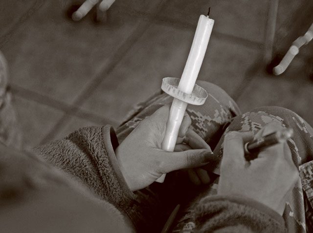A participant attending a candlelight vigil writes down the name belonging to a victim of interpersonal violence Oct. 27 on Ramstein. Those who took part in the vigil put the names they’d written into a glass jar and then lit their candle by one of the four differently marked candles surrounding the jar.