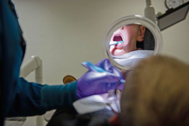 Channing Wray, holds a mirror to watch as his dentist cleans his teeth during the “Little Teeth, Big Smiles” event Nov. 5 on Ramstein.