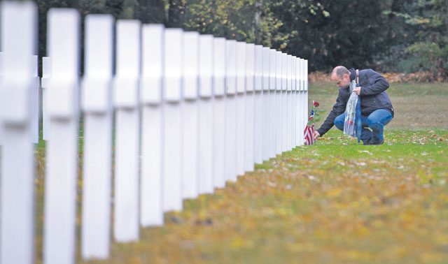 Eric Schell, a French citizen, lays a U.S. flag and flowers on the gravestone of a deceased war veteran Nov. 11 at the Lorraine American Cemetery in St. Avold, France.