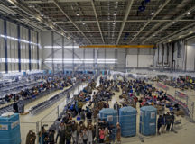 Evacuees prepare to leave Ramstein and head to other transient locations during Operation Allies Refuge at Ramstein Air Base, Germany, Aug. 30, 2021. In order to process passengers seeking transport to their next destination, 521st Air Mobility Operations Wing Airmen have repurposed their maintenance hangar into a small international airport to build a cohesive system in coordination with the Department of State, Transportation Security Administration and other agencies. Partitions are used to separate different outgoing flights during processing. Operation Allies Refuge is facilitating the quick, safe evacuation of U.S. citizens, Special Immigrant Visa applicants, and other at-risk Afghans from Afghanistan. Evacuees receive support such as temporary lodging, food and water, and access to medical care at Ramstein Air Base while preparing for transportation to their final destinations. (U.S. Air Force photo by Senior Airman Milton Hamilton)