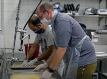 An evacuee, right, and Ben Furqueion, 86th Force Support Squadron business operations flight chief, left, wash rice during food prep at Ramstein Air Base, Germany, Sept. 13, 2021. The evacuees made a meal for the 786th Force Support Squadron and the 86th Force Support Squadron staff to demonstrate the kind of spices and ingredients used in a customary Afghan dish. Evacuees receive temporary lodging, food and water, and access to medical care at Ramstein while awaiting transportation to other transient locations. (U.S. Air Force photo by Senior Airman Milton Hamilton)