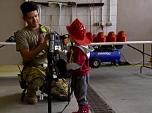 U.S. Air Force Airman 1st Class Mason R. Kim, 86th Civil Engineer Squadron fire department fire fighter, helps a child into firefighting gear during a Fire Prevention Week open house at Ramstein Air Base, Germany, Oct. 22, 2022. President Calvin Coolidge proclaimed Fire Prevention Week anational observance in 1925, which makes it the longest-running national health observance in the United States. (U.S. Air Force photo by Jennifer Green-Lanchoney)