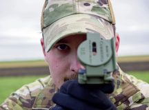 U.S. Air Force Staff Sgt. Hunter Rhoden, 86th Operations Support Squadron air traffic controller, peers through a lensatic compass while setting up landing zone marking panels at Chièvres Air Base, Belgium, Feb. 13, 2024. A combined team of air traffic controllers, airfield operations officers, radar airfield weather systems technicians and airfield managers earned their landing zone safety officer certification on Feb. 11 – 15, 2024. This special experience identifier allows them to perform the LZSO function in all environments. (U.S. Air Force photo by Staff Sgt. Robert L. McIlrath)