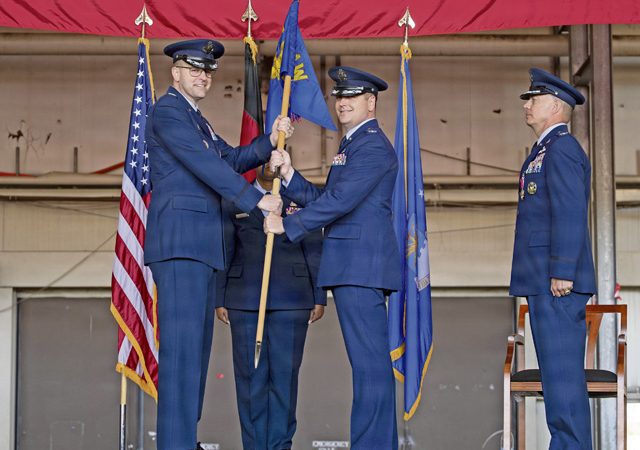 U.S. Air Force Col. Denny R. Davies, 86th Airlift Wing commander, transfers command of the 86th Logistics Readiness Group to Col. Benjamin J. Schneider, 86th LRG incoming commander, during a change of command ceremony at Ramstein Air Base, Germany, July 10, 2026. The transfer of the guidon symbolizes the formal assumption of command and responsibility for the unit and its mission. (U.S. Air Force photo by Senior Airman Olivia Sampson)